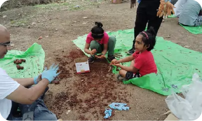 Participants including children making seedballs during CSR activity 